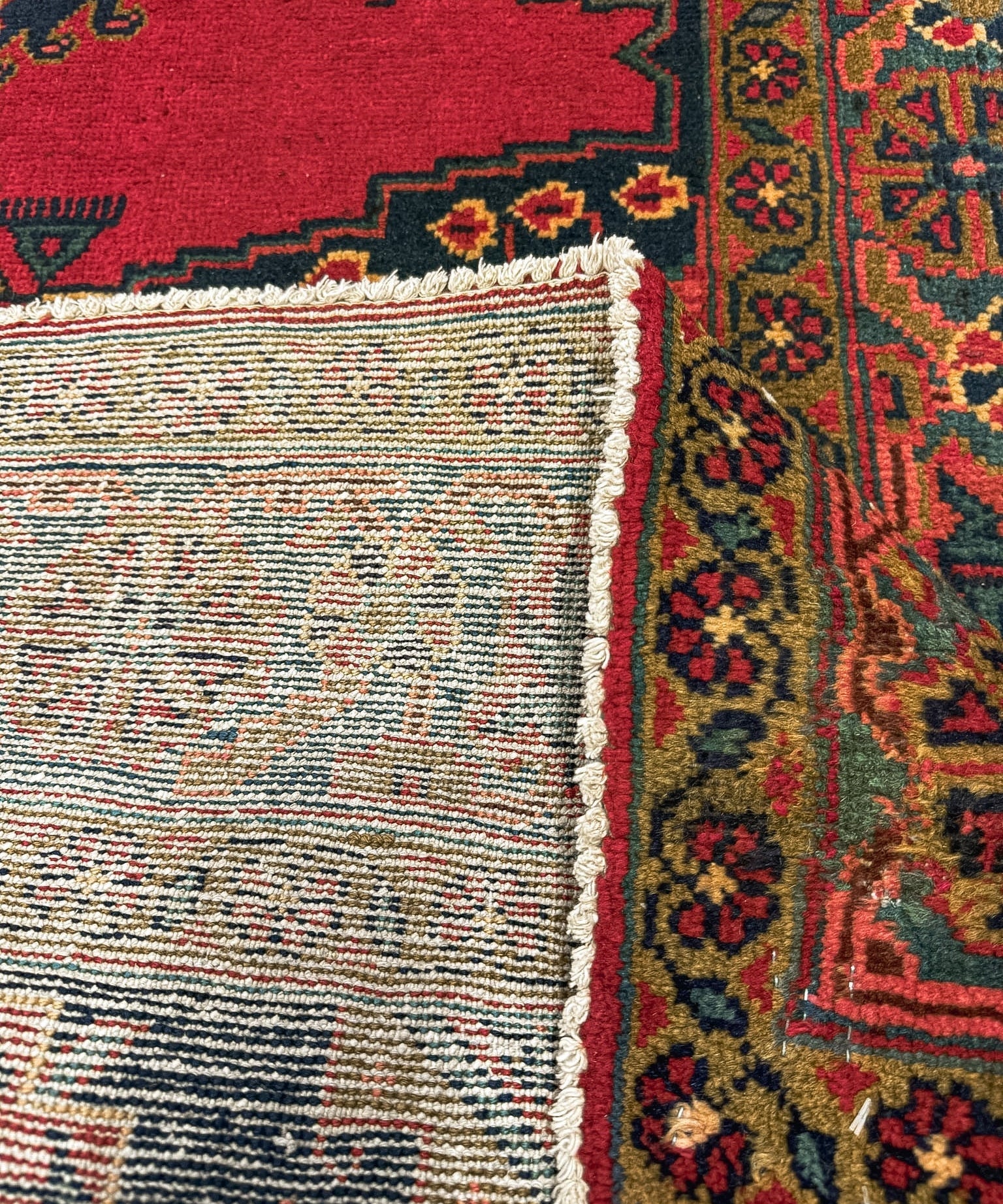 Red Persian rug with woven edge and fringe, plus multicolor medallion and border