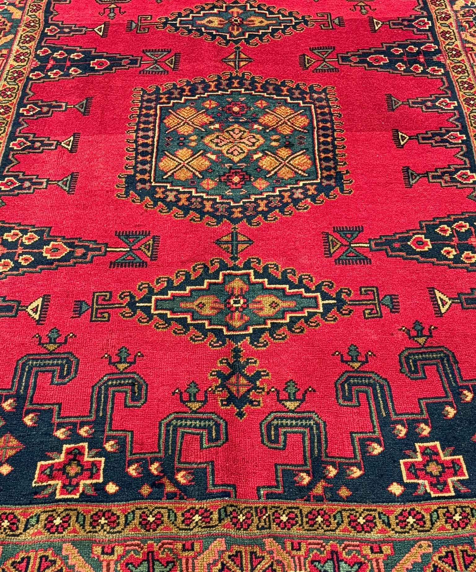 Red Persian rug close view with central medallion and multicolor geometric corner motifs