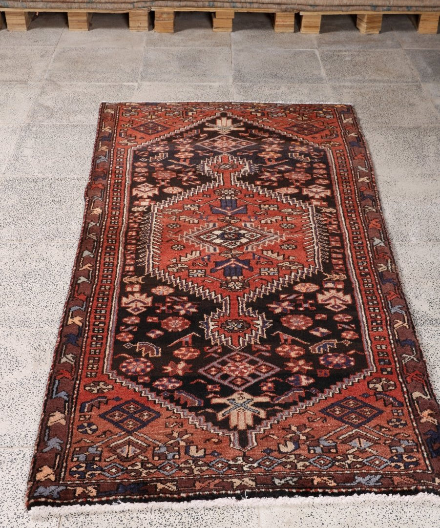 Rectangular Persian rug in dark red and black with cream diamond and border motifs