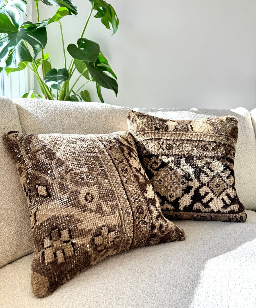 Set of patterned square pillows on a gray sofa cushion, brown and beige tones.