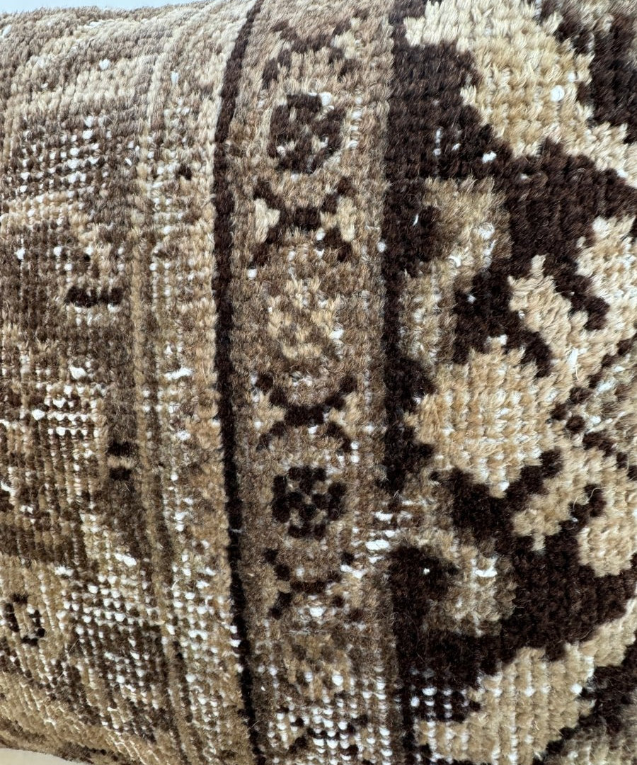 Brown and beige geometric tapestry pillow with textured woven fabric and patterned panel.