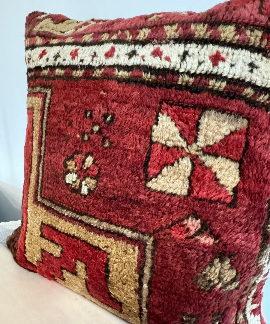 Red decorative pillow with cream star motif, outlined borders, and textured woven fabric.