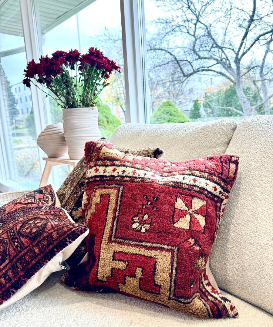 Square red patterned throw pillow with geometric motifs and fringe trim