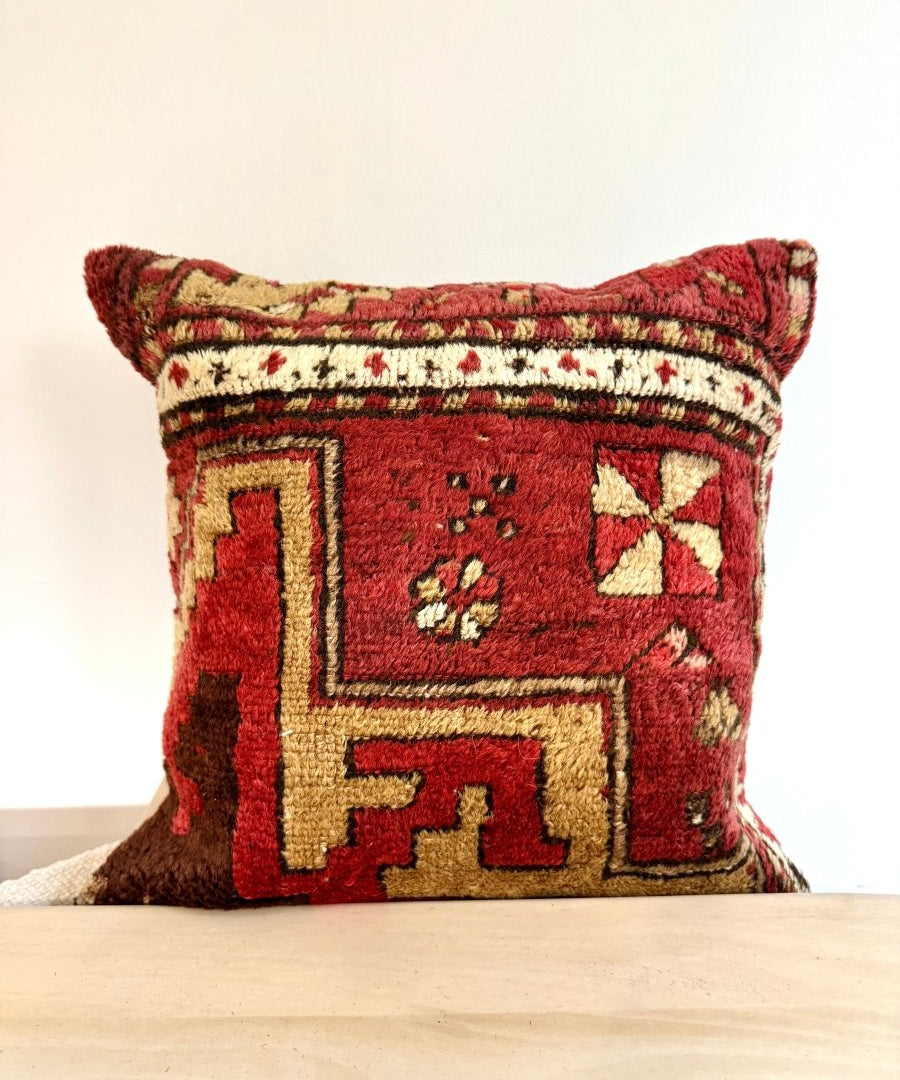 Red decorative throw pillow with cream geometric embroidery and fringe trim, 16x16 in.