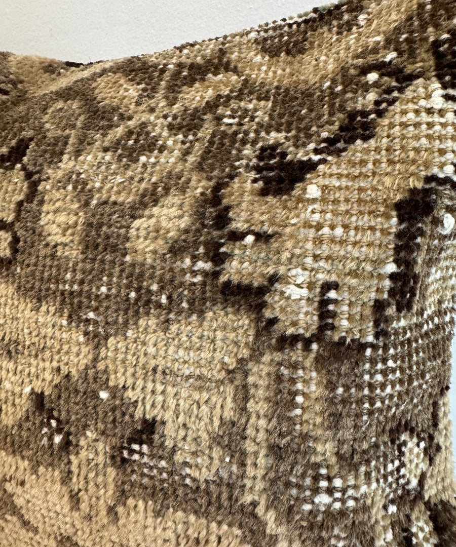 Detail view of woven pillow with textured beige and dark motifs