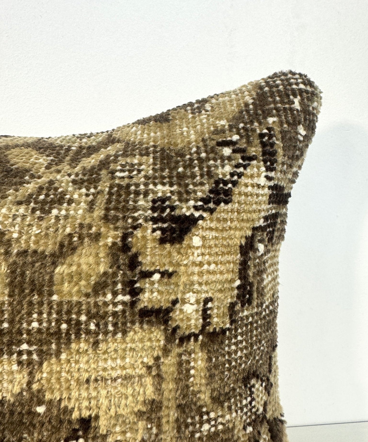 Decorative square pillow close-up of olive and dark abstract geometric pattern on woven fabric