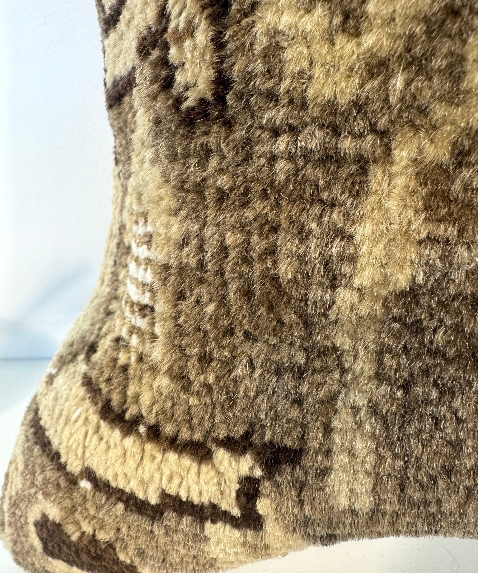Decorative pillow front with dense woven texture in olive-brown and dark motif accents