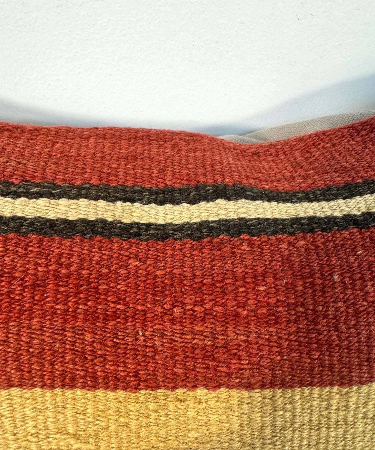 Striped pillow fabric close-up with orange-red, beige, and dark gray bands