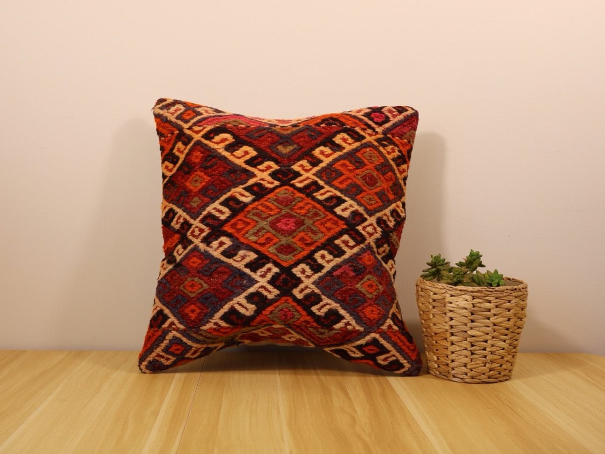 Decorative pillow with geometric kilim-style pattern, orange and red tones with black and cream