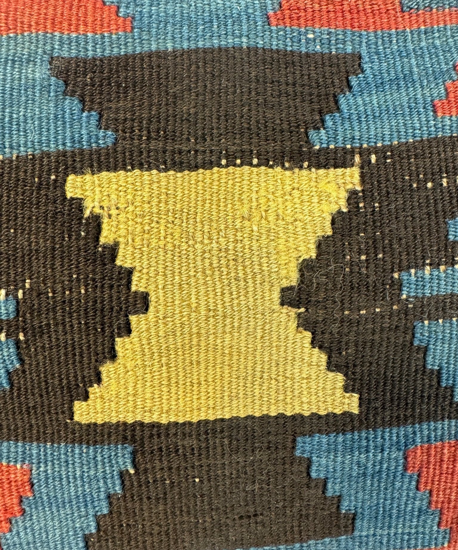 Decorative pillow close-up: dark and yellow diamond center with blue and red edges.