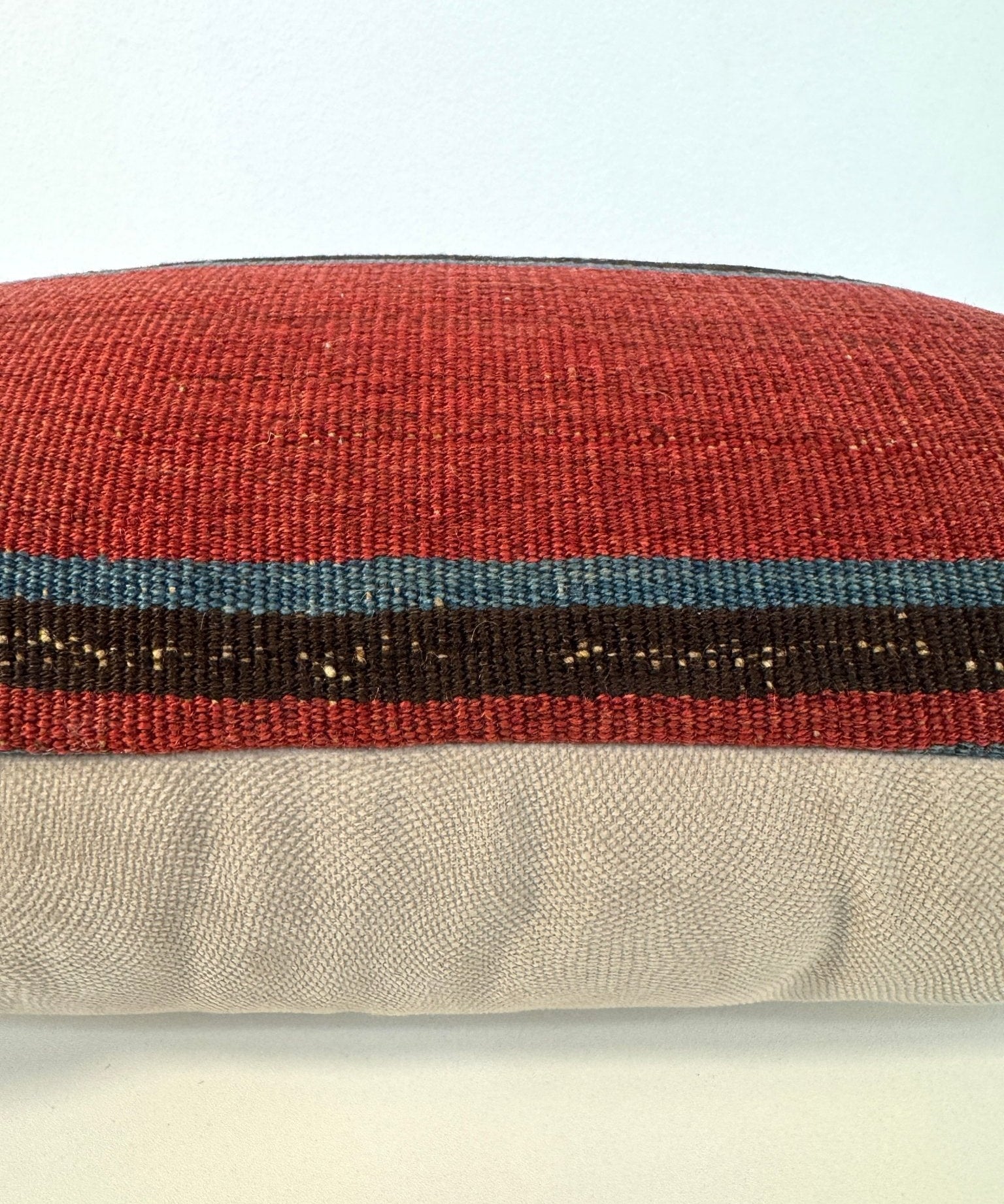 Multicolor woven pillow fabric close-up with red, teal, and dark stripe bands