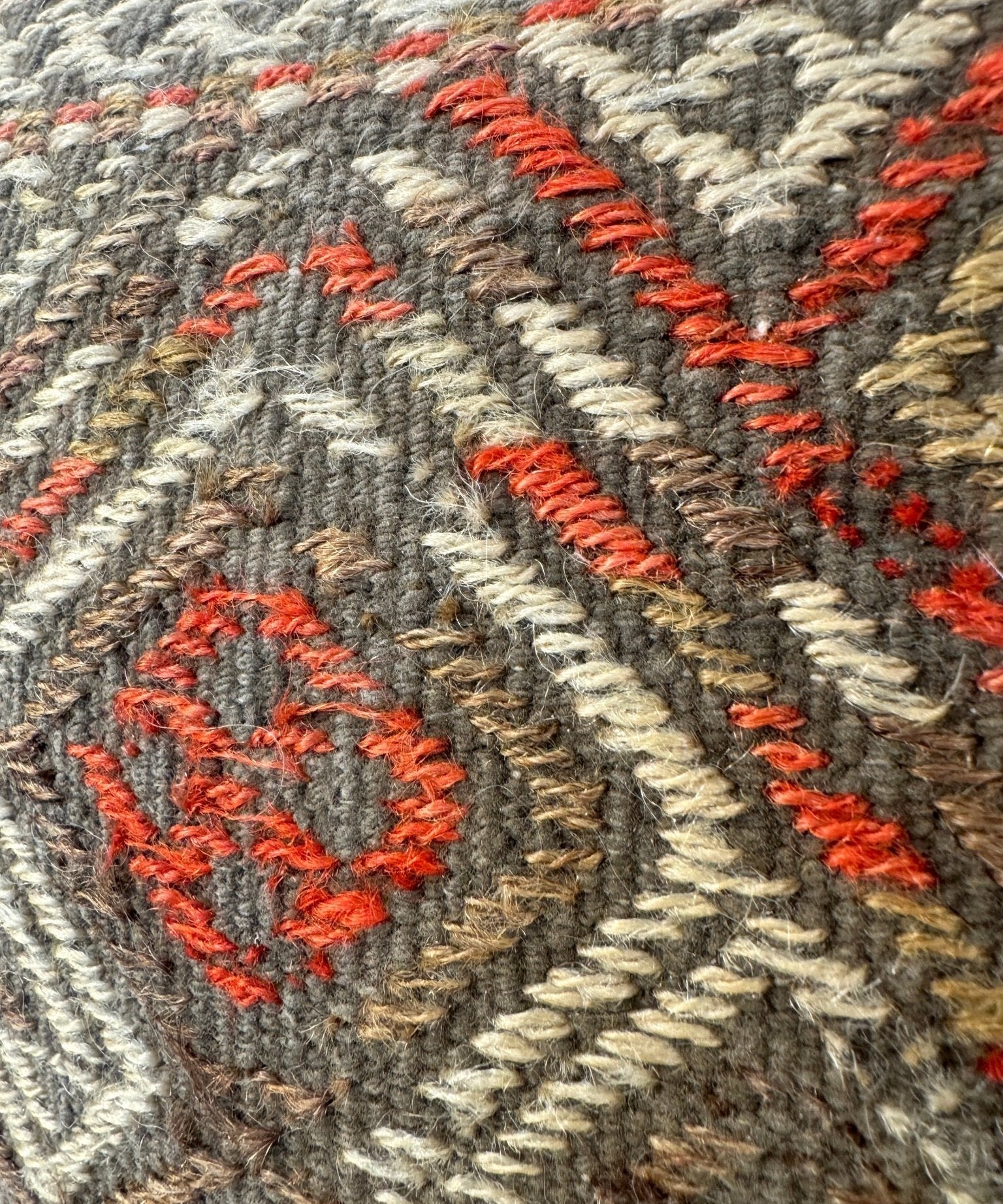 Textured pillow cover detail with red geometric stitching on mottled dark fabric