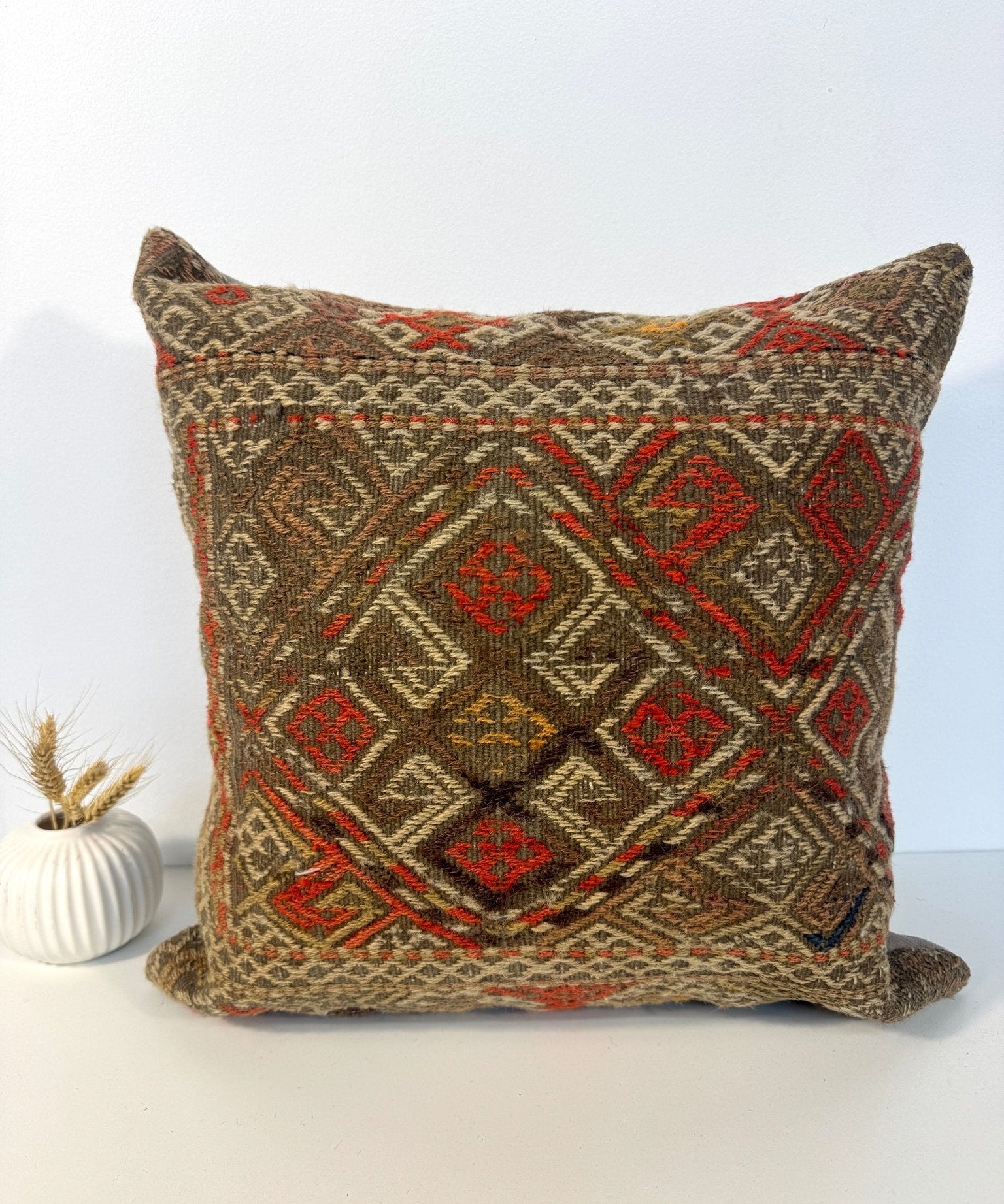 Decorative 18" x 18" woven pillow with dark brown base and red geometric diamond design
