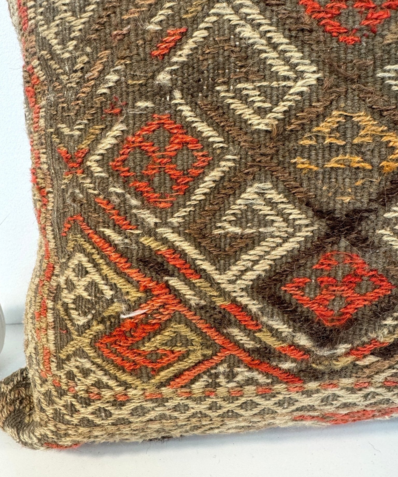 Woven pillow cover side with dark brown base and multicolor diamond motif pattern