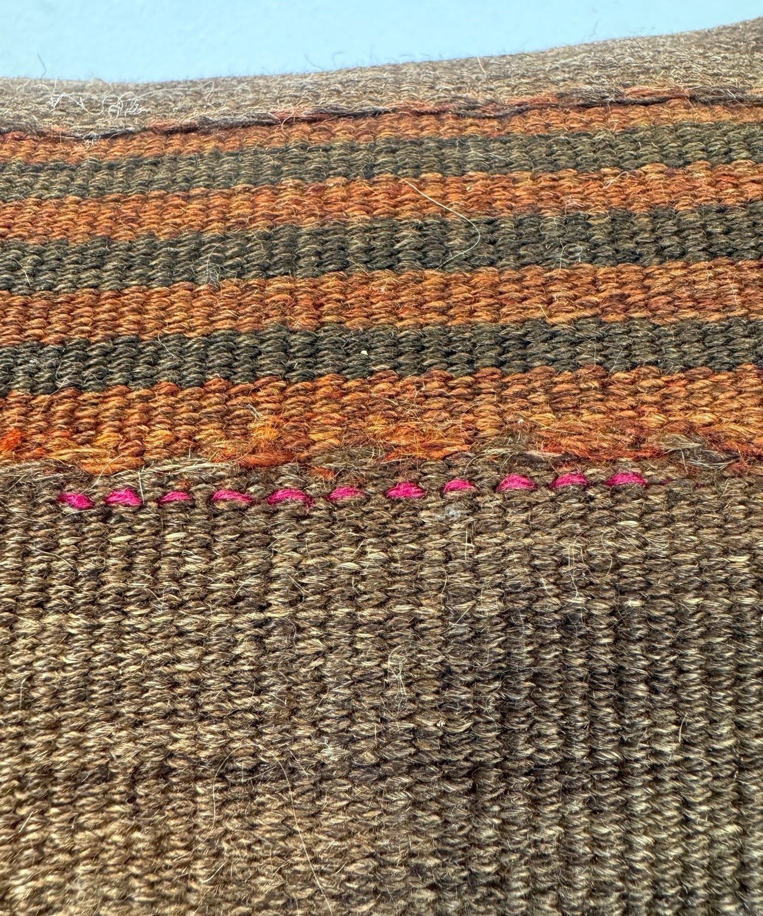 Woven pillow, 16 x 16 in, brown with pink stitched trim along the bottom edge