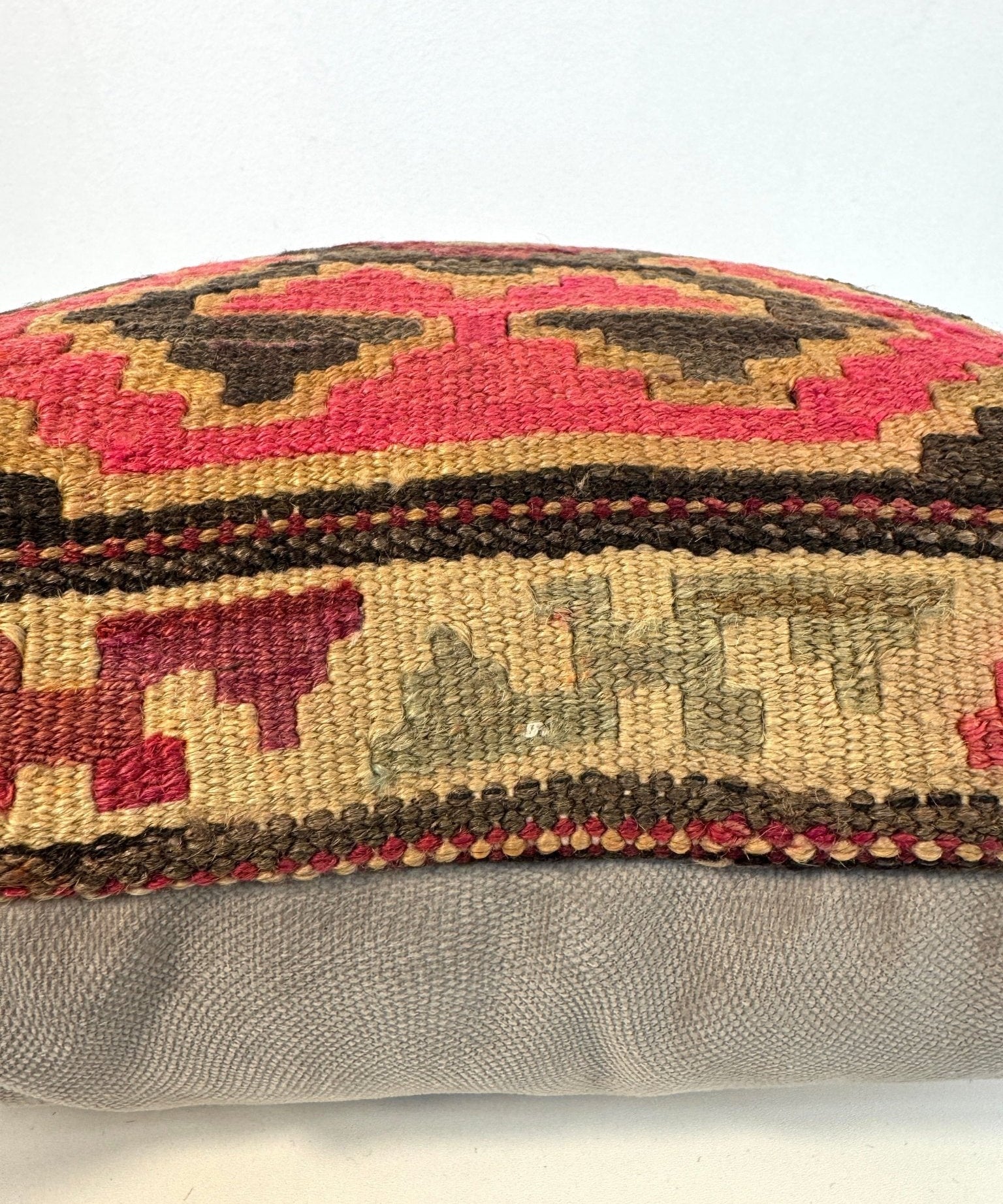 Multicolor patterned kilim pillow cover with stitched edge and layered geometric bands.
