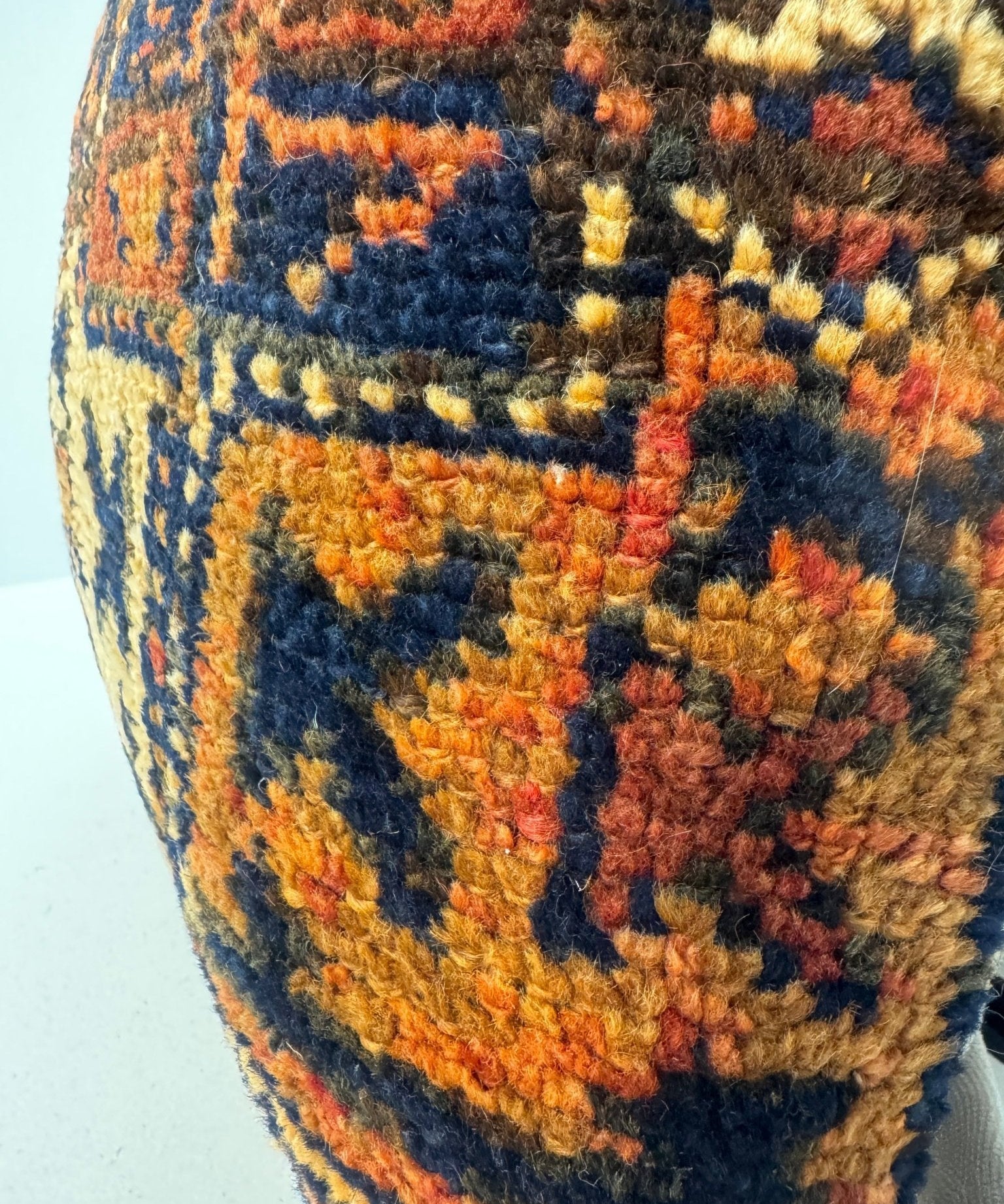 18 x 18 woven pillow corner with multicolor geometric stitches in navy, orange, and red
