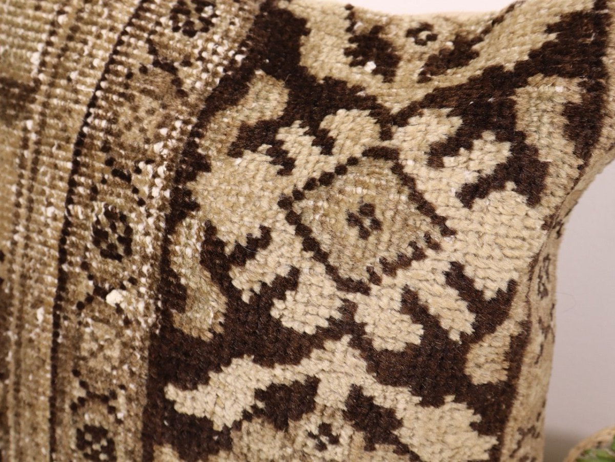 Brown and cream patterned decorative pillow front, close-up of geometric motifs