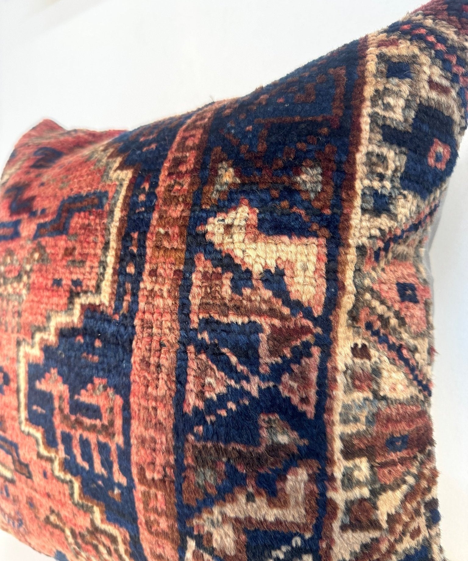 Decorative 18x18 pillow closeup with navy border and red geometric motifs