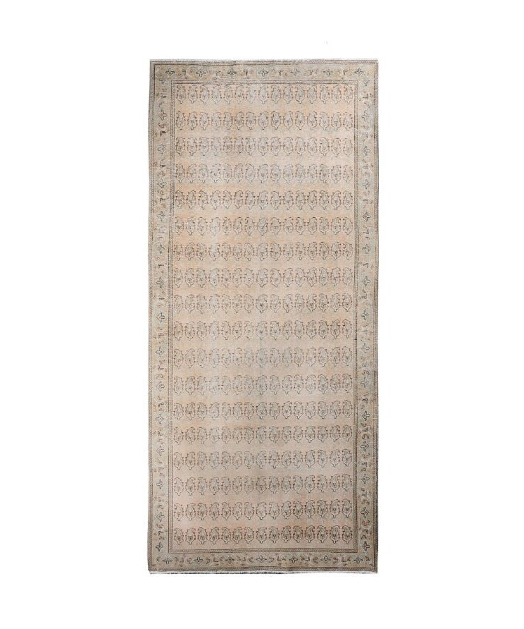 Rectangular beige paisley rug with central field of repeating motifs and patterned border