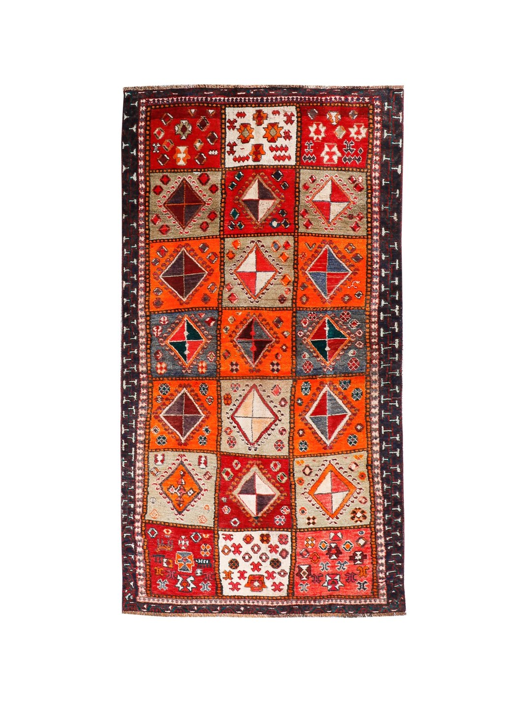 Persian Shiraz rug with red-orange field, cream diamonds, navy border and fringe.