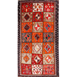Persian Shiraz rug with red-orange field, cream diamonds, navy border and fringe.