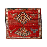 Red Persian-style rug with diamond medallion, birds, and multicolor border design.