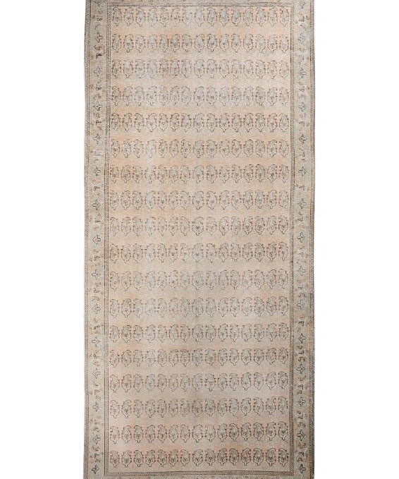 Rectangular beige paisley rug with central field of repeating motifs and patterned border