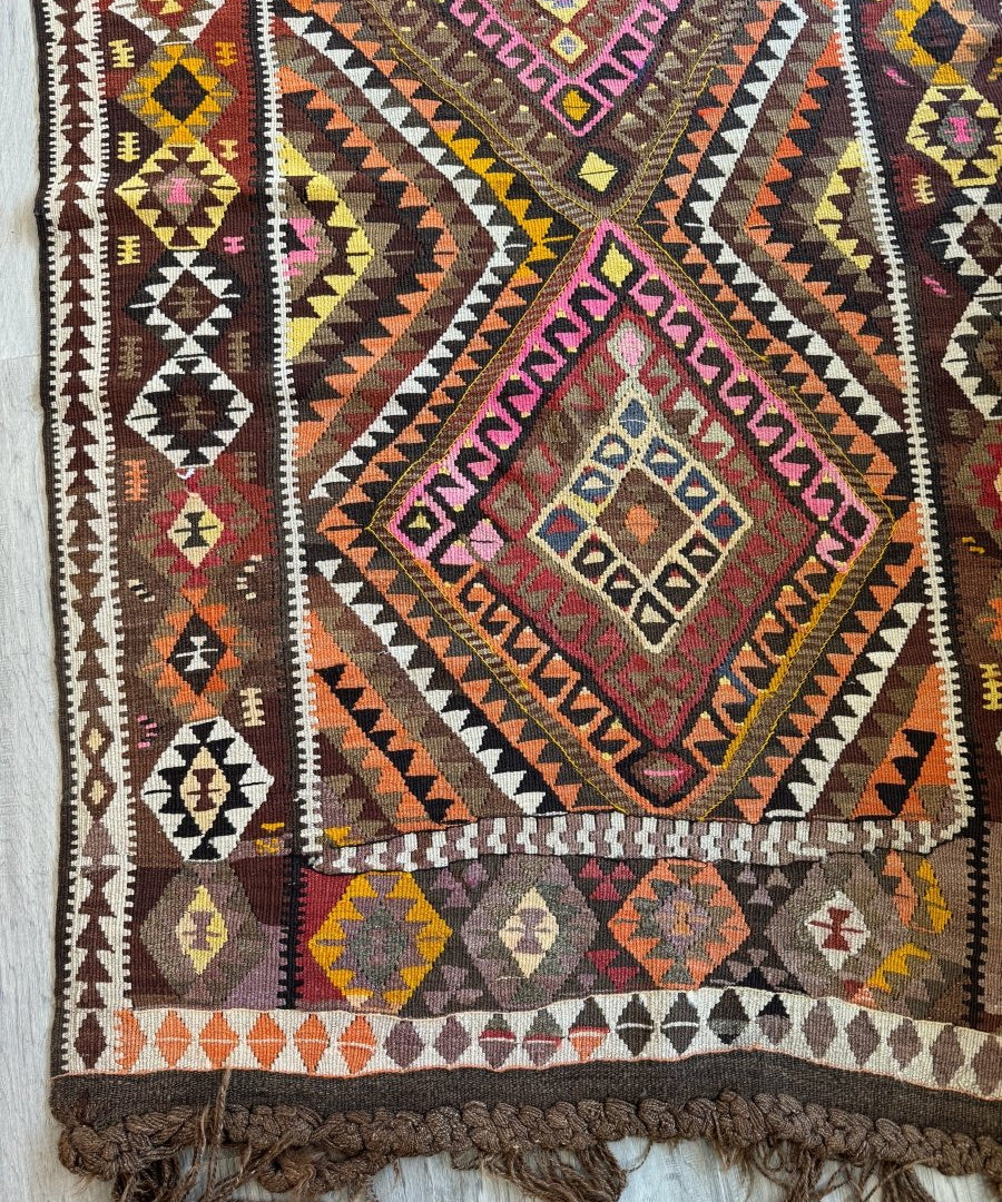 Kilim rug with multicolor geometric medallions, zigzags, and tassel fringe border.