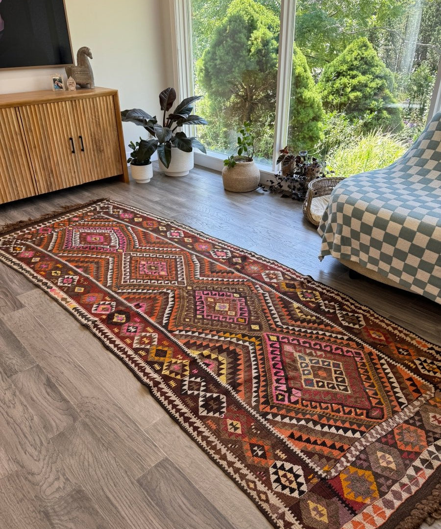 Multicolor Turkish-style kilim rug with geometric pattern and short dark tassel fringe.