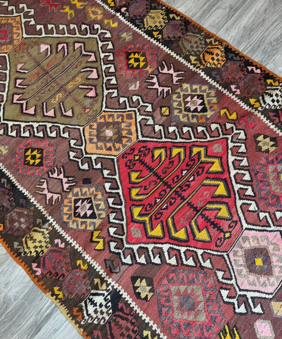 Kilim runner rug with multicolor zigzag lines, stars, and diamond motifs on maroon