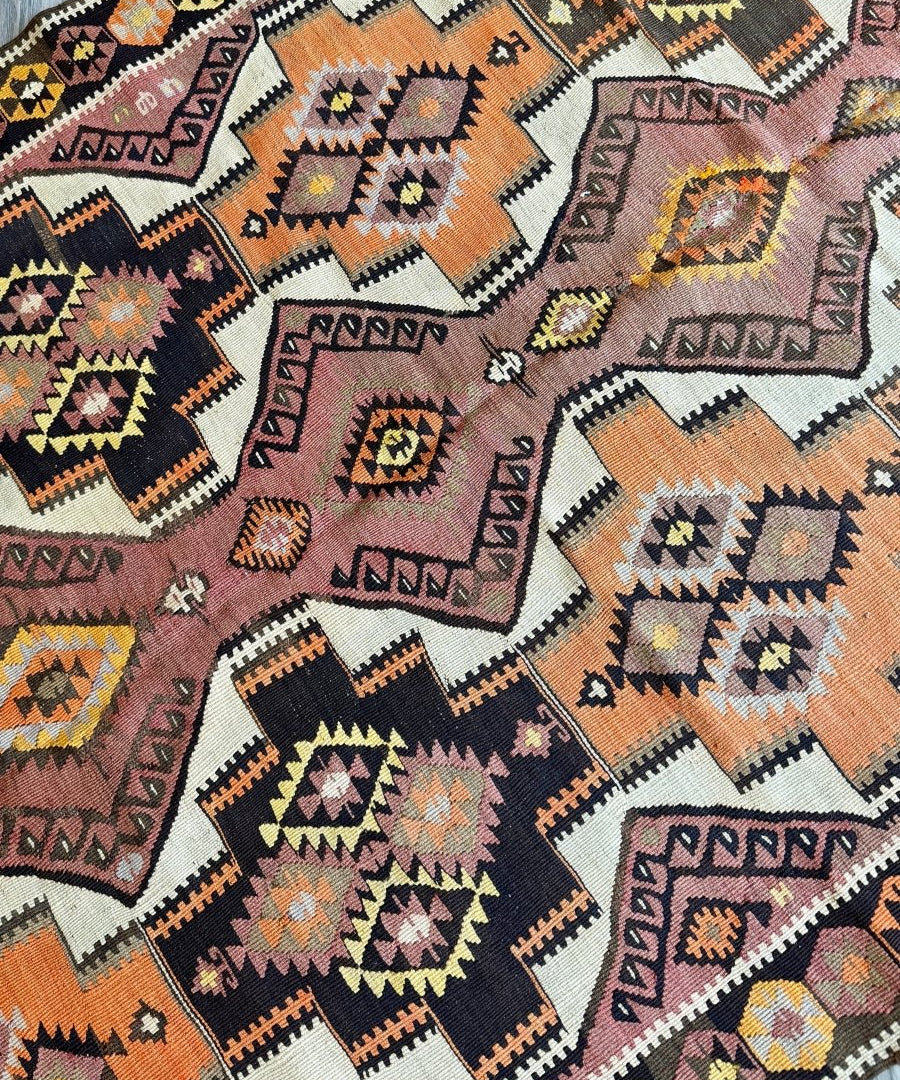 Kilim runner rug close-up of multicolor diamond and zigzag motifs on light ground.