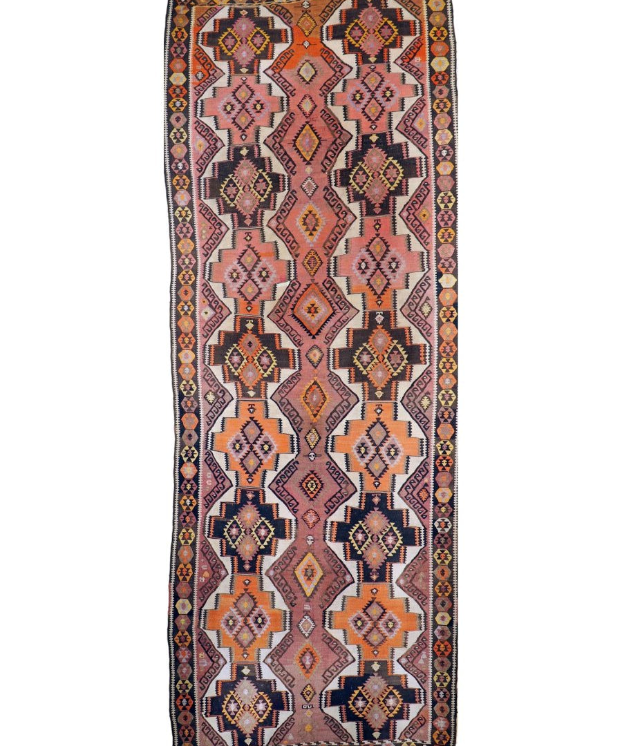 Kilim runner rug with symmetrical diamond pattern and dark border on a light base.