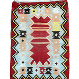 Turkish kilim rug with red background, geometric diamonds, and zigzag border