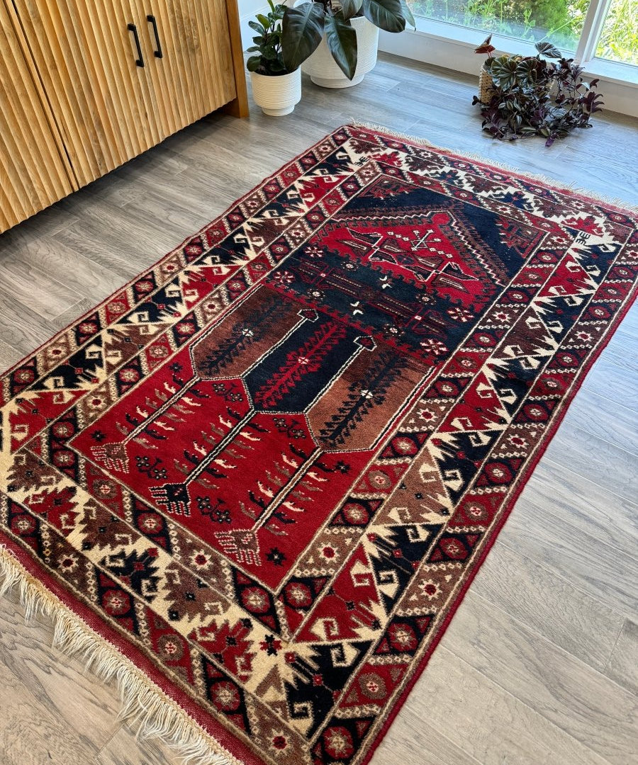Turkish Konya rug laid flat with red and navy panels, cream borders, and decorative motifs
