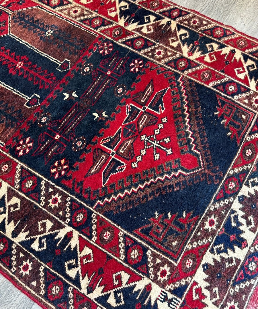 Turkish Konya rug close-up showing dark navy center medallion with red accents and borders