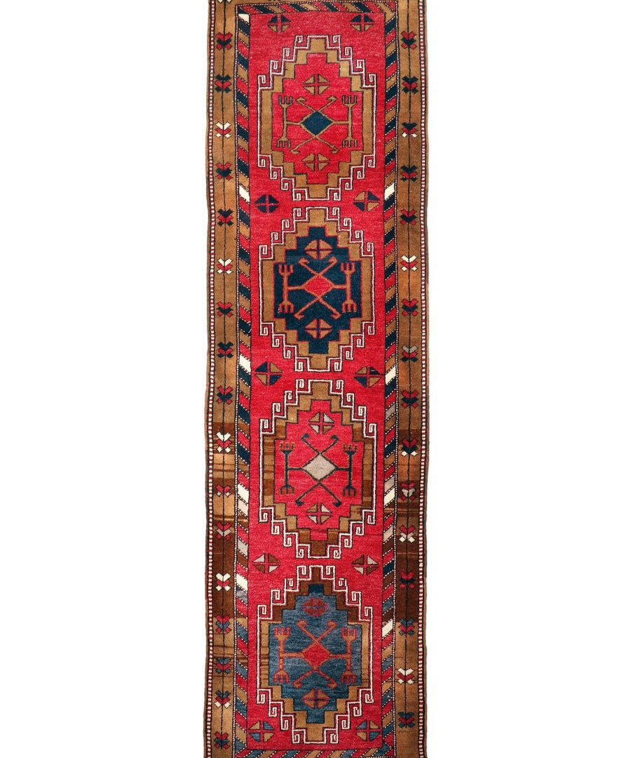 Runner rug with red and navy medallion panels, tan field, and fringed ends.