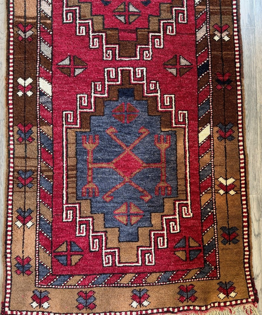 Runner rug with red, navy, and tan geometric medallion and border; short fringe edge.