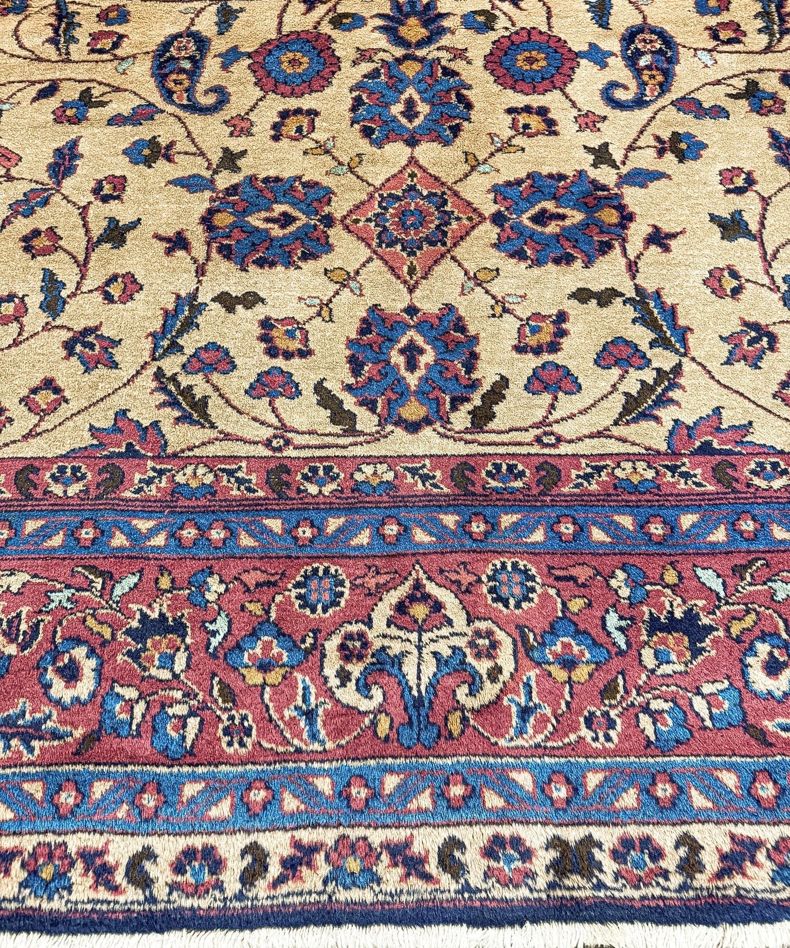 Close-up of Oushak rug border: cream field with blue and red diamond floral pattern