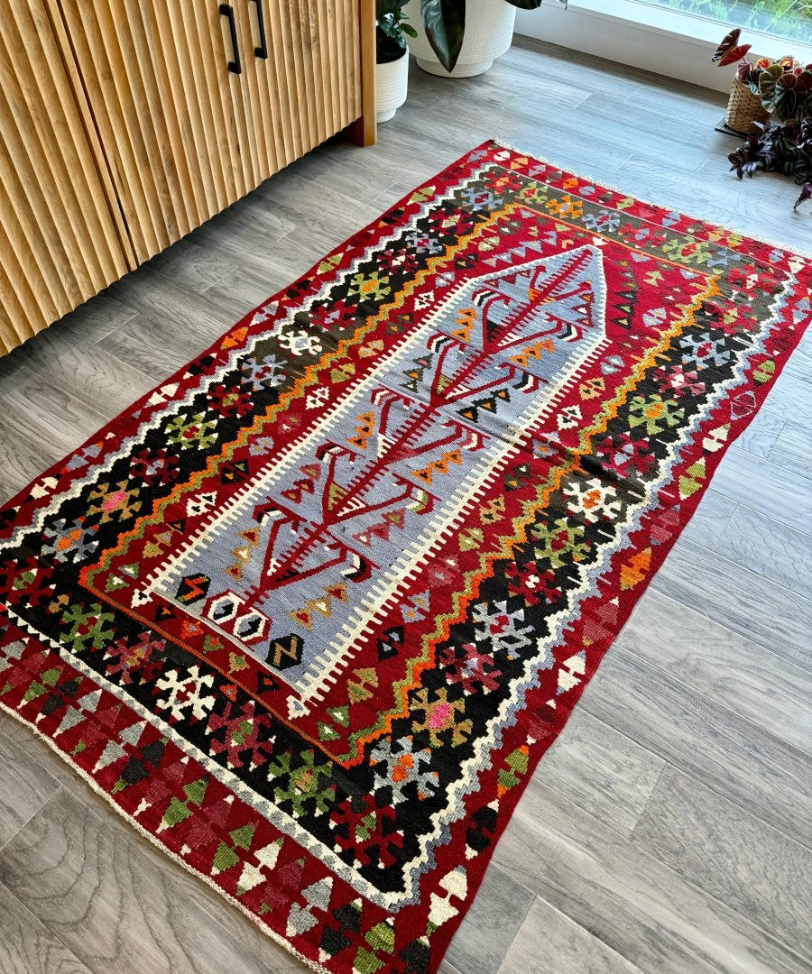 Rectangular Turkish kilim rug in red, gray, and multicolor with central medallion pattern.