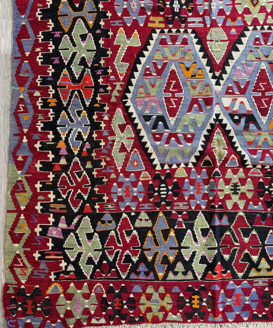 Geometric Turkish kilim rug with red field, black accents, and multicolor motifs