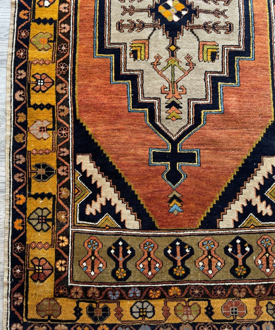 Turkish patterned area rug with rust red field, navy borders, and central geometric medallion.