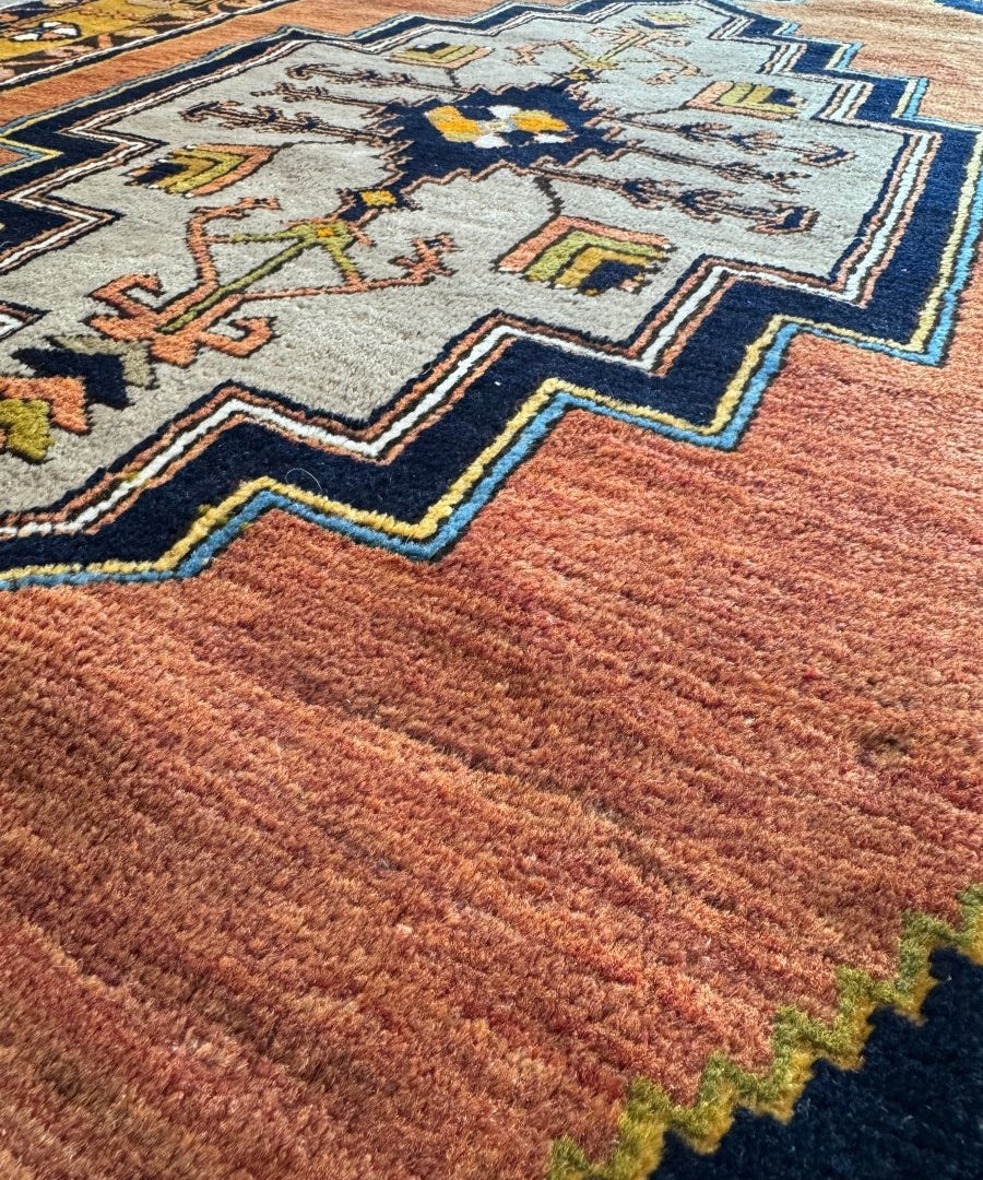 Turkish area rug with rust red pile, light gray central medallion, and blue zigzag trim.