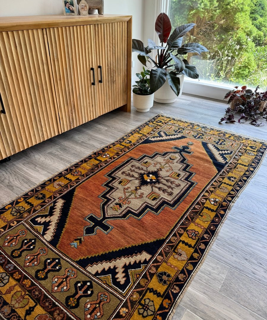 Turkish area rug with rust red center, navy and teal geometric motifs, and zigzag border.