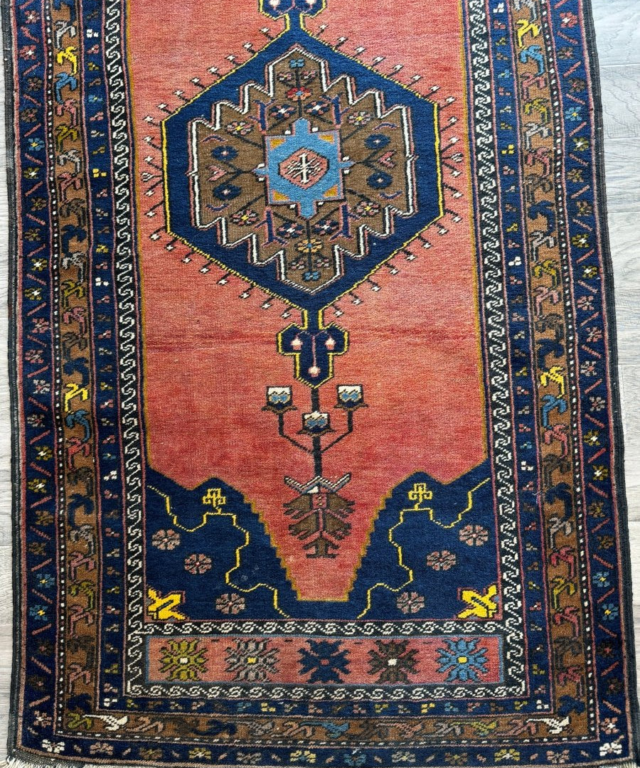 Turkish style rug with red field, blue geometric medallion, and decorative border stripes.
