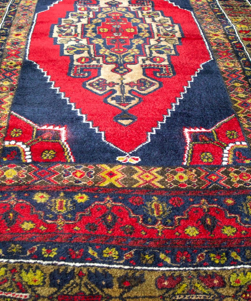 Turkish rug front view with red diamond medallion, navy background, and colorful border
