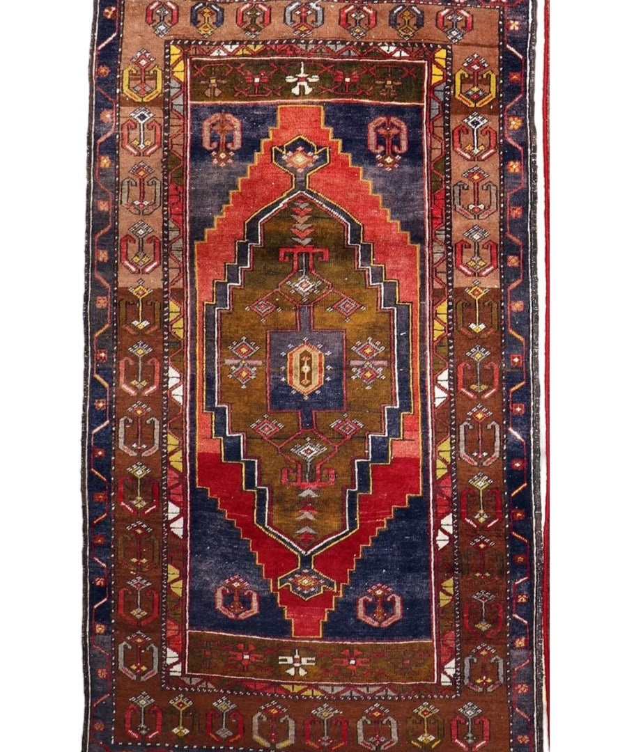 Turkish rug full view with rectangular border, red center panel, and dark blue geometric patterning.