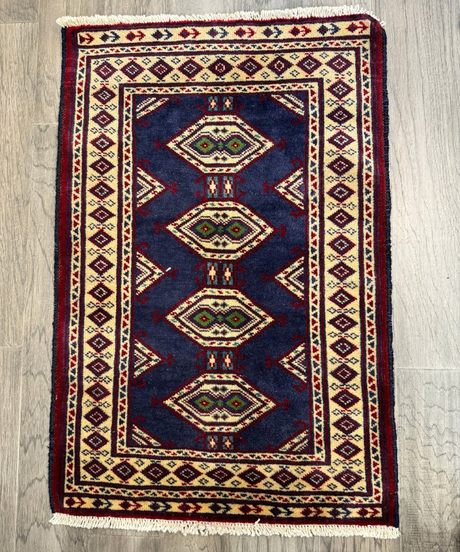 Turkmen mini rug with dark navy field, stacked diamond medallions, red and cream framed border, fringe