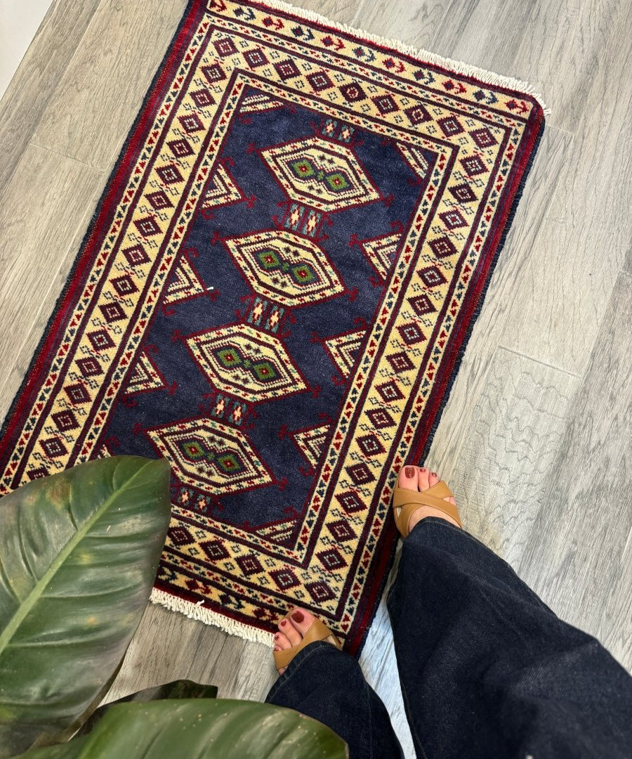 Turkmen mini rug with dark navy field, red and cream geometric border, short fringe edges