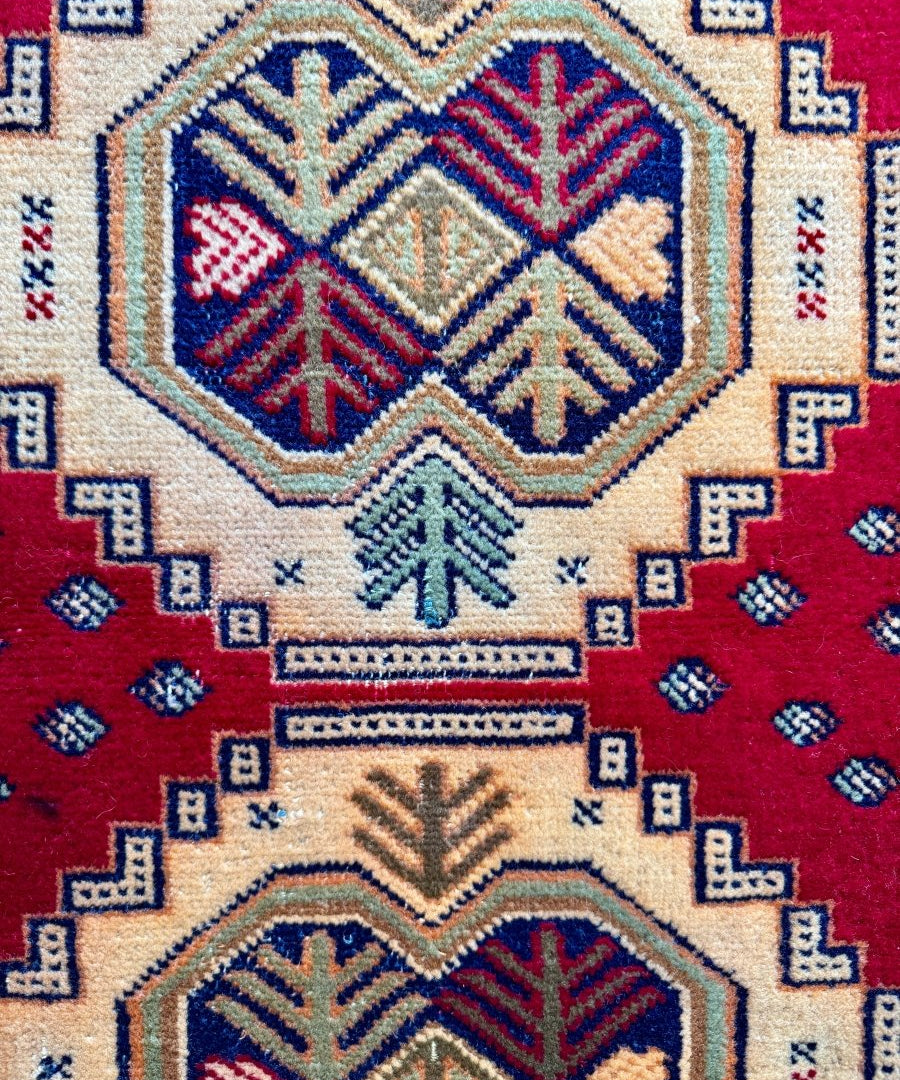 Turkmen mini rug close-up medallion with ivory background, red and blue arrow/tree motifs